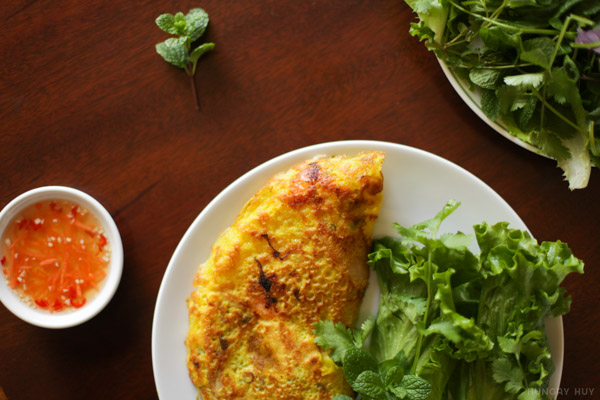 A single serving of banh xeo with a side of fish sauce