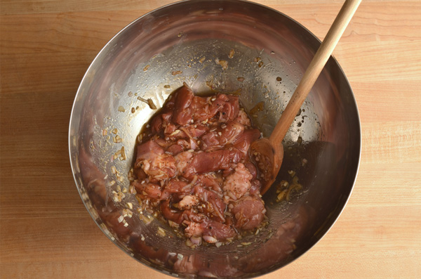 adding pork to the bowl to marinade