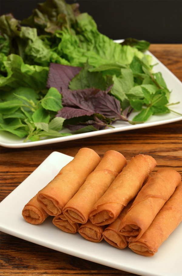 plate of fried egg rolls, with herb and lettuce plate